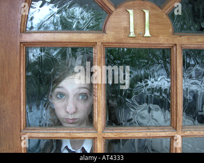 teenage girl with face pressed against glass at her front door Stock Photo