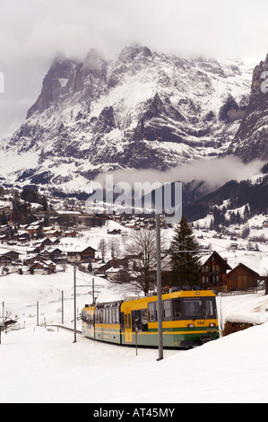 Grindelwald to Kleiner scheidegg funicular railway train with Grindelwald and The Wetterhorn mountain behind. Stock Photo