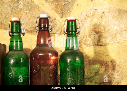 Bottles containing alcohol in front of a stone wall Stock Photo