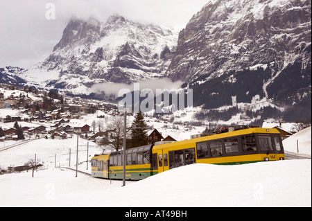 Grindelwald to Kleiner scheidegg funicular railway train with Grindelwald and The Wetterhorn mountain behind. Stock Photo