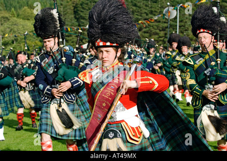 Scottish traditional pipe band majorette leads bagpipe band at the Lonach Highland Games at Strathdon, near Balmoral, Scotland Stock Photo