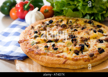 A hot mozzarella & olive Pizza pie presented with fresh produce on a wooden platter Stock Photo