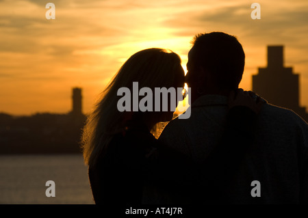 Young couple embracing at sunset on the quayside looking over the River Mersey Liverpool UK Stock Photo