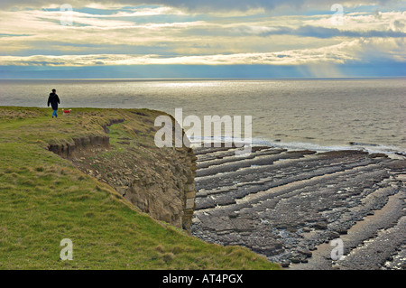 A walker at Nash Point on the South Wales Coast looking out to Somerset Stock Photo
