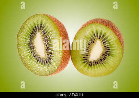 Two kiwi fruit cut on matching green background Stock Photo