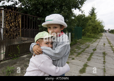 Young children hugging each other outdoors, brothers on the path Stock Photo