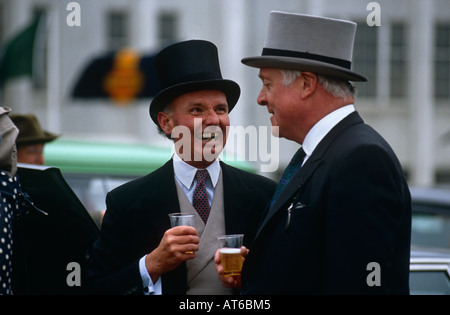 Two men drinking champagne at a picnic in the car park on Derby Day at Epsom racecourse, Surrey UK Stock Photo