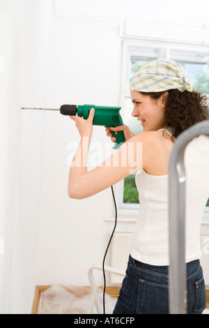 Young woman using drill Stock Photo