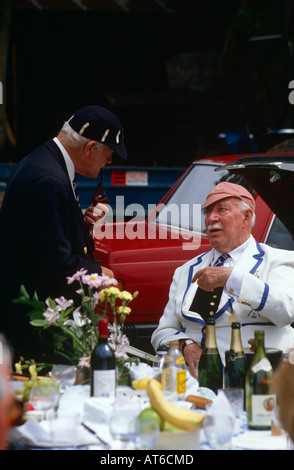 Two old men wearing rowing club caps and blazers chatting in the car park at Henley Royal Regatta, Oxfordshire UK Stock Photo