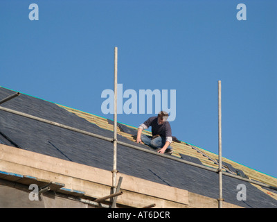 Man fixing slates onto a roof of house in Cardigan Town Ceredigion West Wales Stock Photo