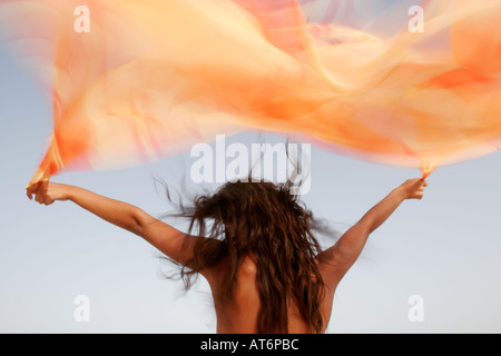 Beauty Picture of woman flying orange material in the wind Stock Photo