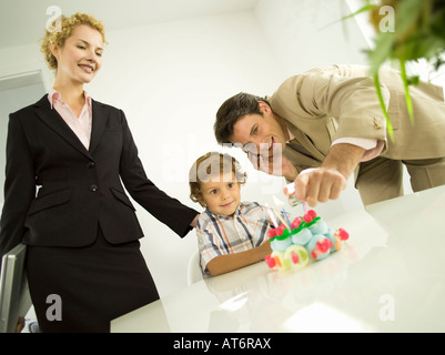 Young family, father lighting candles on birthday cake Stock Photo