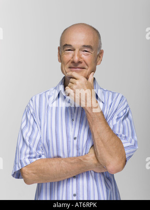 Senior man resting chin on hand, smiling, portrait Stock Photo