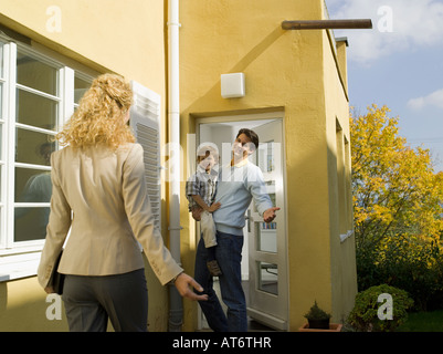 Father at door holding boy (3-4), mother coming home Stock Photo