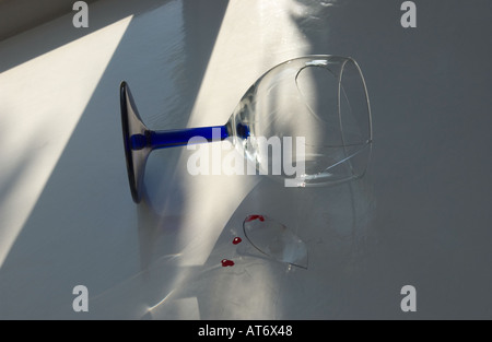 A blue stemmed wineglass lies broken on a windowsill Stock Photo