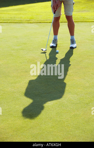 Austria, Male golfer preparing to drive ball, low section Stock Photo