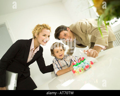 Young family, father lighting candles on birthday cake Stock Photo