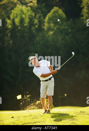 Austria, Male golfer swinging club on fairway Stock Photo