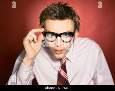 Young caucasian hipster business guy in pink shirt tying a striped tie in the studio. Stock Photo