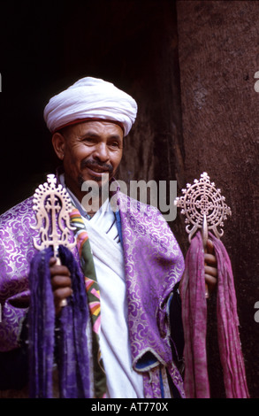 An Ethiopian orthodox preist holds the colorful cross in the enterance of one of the old stone carved churches of Lalibela Stock Photo