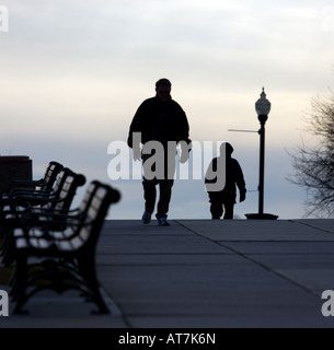 Walkers walk along a boardwalk in West Haven Connecticut USA during the winter during a bitter cold day in February Stock Photo