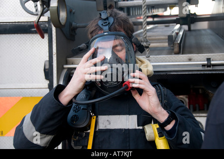 fireman removing his breathing apparatus after dealing with a 999 emergency call out Stock Photo