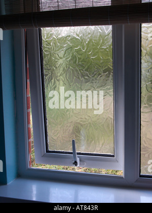 handle on double glazed bathroom window opened to garden with bamboo curtain Stock Photo