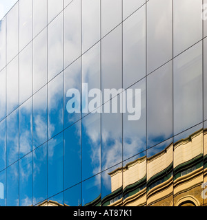 Mirrored sky reflections contrast period architecture in modern office windows Stock Photo