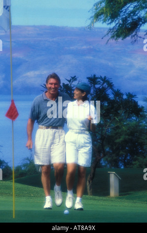 Couple walking to towards the putting greens on a golf course Stock Photo