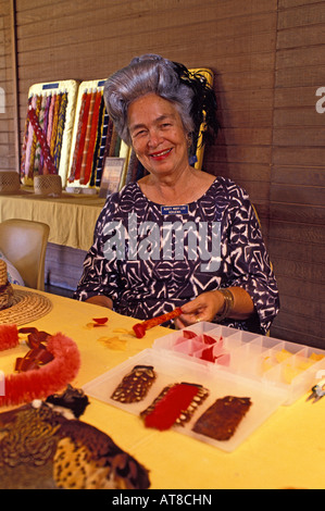 A female kapuna (elder) smiles as she sits at a table with feather lei making materials at Bishop Museum. Stock Photo