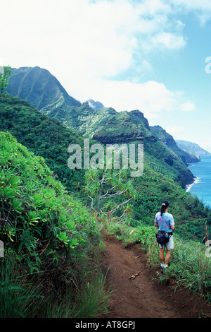Hiker enjoys coastline views from the Kalalau Trail, an 11-mile trail along the Na Pali Coast, Kauai's remote north shoreline Stock Photo