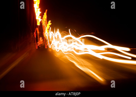 blurred car lights driving along road at night Stock Photo