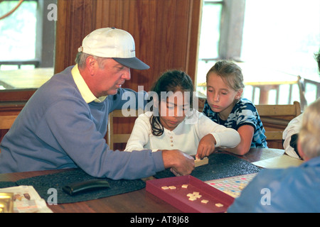 Grandpa age 60 and granddaughters playing scrabble game age 7 & 8. Cedarville Michigan USA Stock Photo