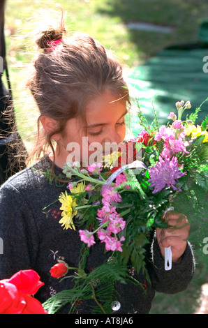 Girl age 7 smelling bouquet of flowers at grandmas funeral. Crystal Lake Cemetery Minneapolis Minnesota USA Stock Photo