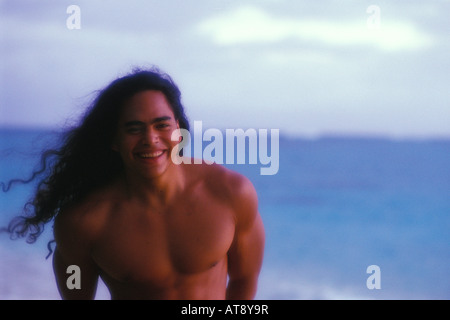 Young Hawaiian man at sunrise on the beach, Oahu Stock Photo