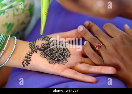 Woman receiving a mendhi henna design on the inside of palm of a her hand in preparation for her hindi wedding ceremony Stock Photo