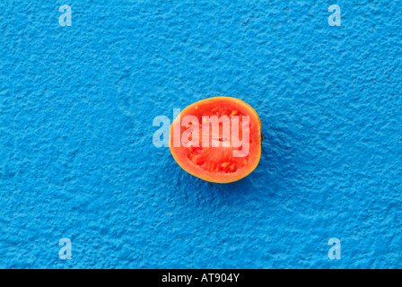 Close up of a pink guava fruit cut in half on blue background Stock Photo