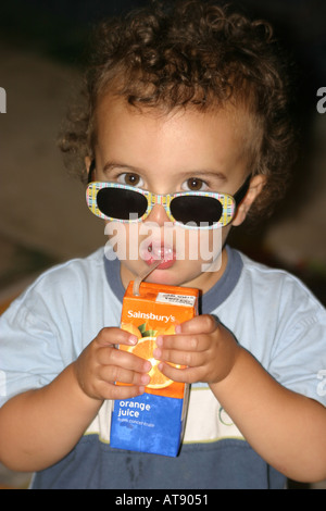 A small boy enjoys a drink of orange juice from a carton Stock Photo