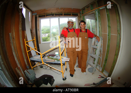 Two men working on a home improvement project with tan overalls and scaffolding taken with a fish eye lens Stock Photo