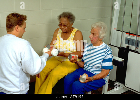 Women age 70 and age 80 working out with trainer age 25 at Lynnwood Recreation Center. St Paul Minnesota MN USA Stock Photo