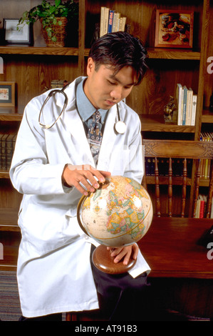 Korean American medic medical physician intern doctor age 24 studying globe in office. St Paul Minnesota MN USA Stock Photo