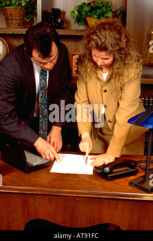 Businessman age 33 consulting with woman partner secretary associate age 32 in office. St Paul Minnesota MN USA Stock Photo