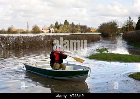 A local resident travelling by boat in a flooded lane near the River Severn at Deerhurst, Gloucestershire UK in March 2007 Stock Photo