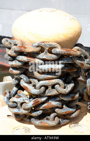Beige mushroom shaped bollard with really large heavy metal chain wrapped around it many times. Stock Photo