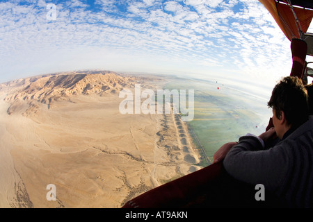 Tourist in hot air balloon admires aerial view of Luxor West Bank Theban Mountains Valley of Kings Egypt North Africa Stock Photo