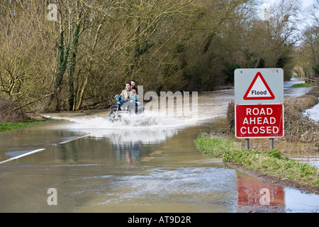 Two lads on a quad bike tackling the B4213 while it was closed due to flooding near Apperley, Gloucestershire in March 2007 Stock Photo