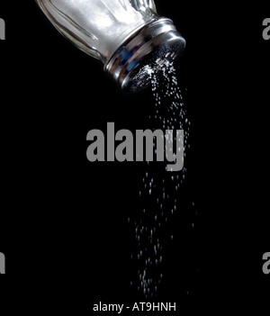 Salt shaker with salt coming out Salt shaker sodium salty falling out coming out Black background food foods Stock Photo