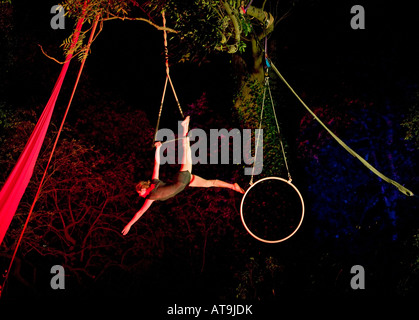 Female trapeze artist hangs from swing against dark background, Edinburgh Fringe Festival, Scotland, UK, Europe Stock Photo