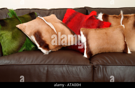 animal hair scatter cushions on brown leather sofa Stock Photo