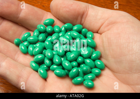 Male hand holding many green pills Stock Photo